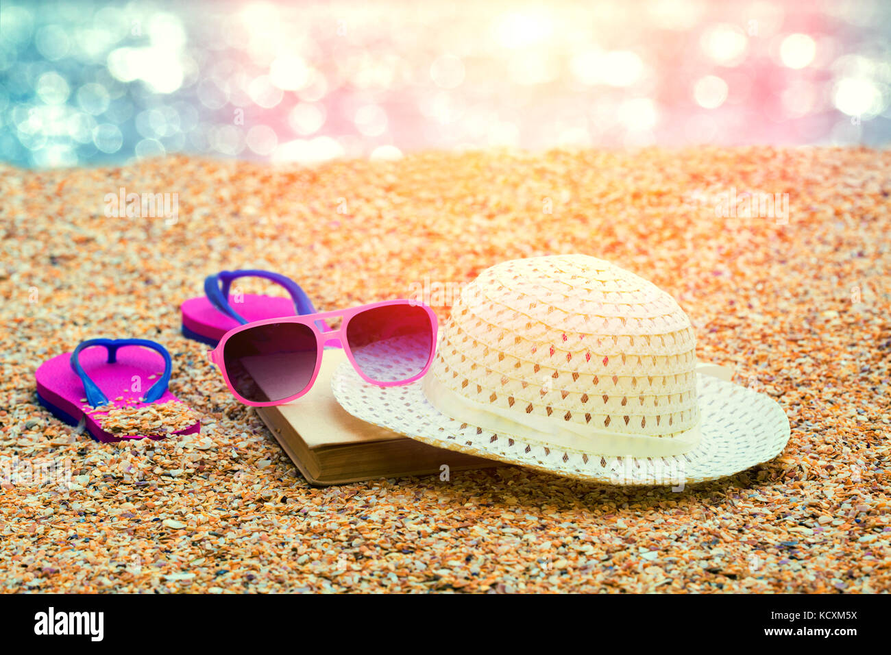 Scena di spiaggia. Sun cappello di paglia, flip flop sandali e occhiali da sole giacente sul mare coquina conchiglie sulla spiaggia Foto Stock