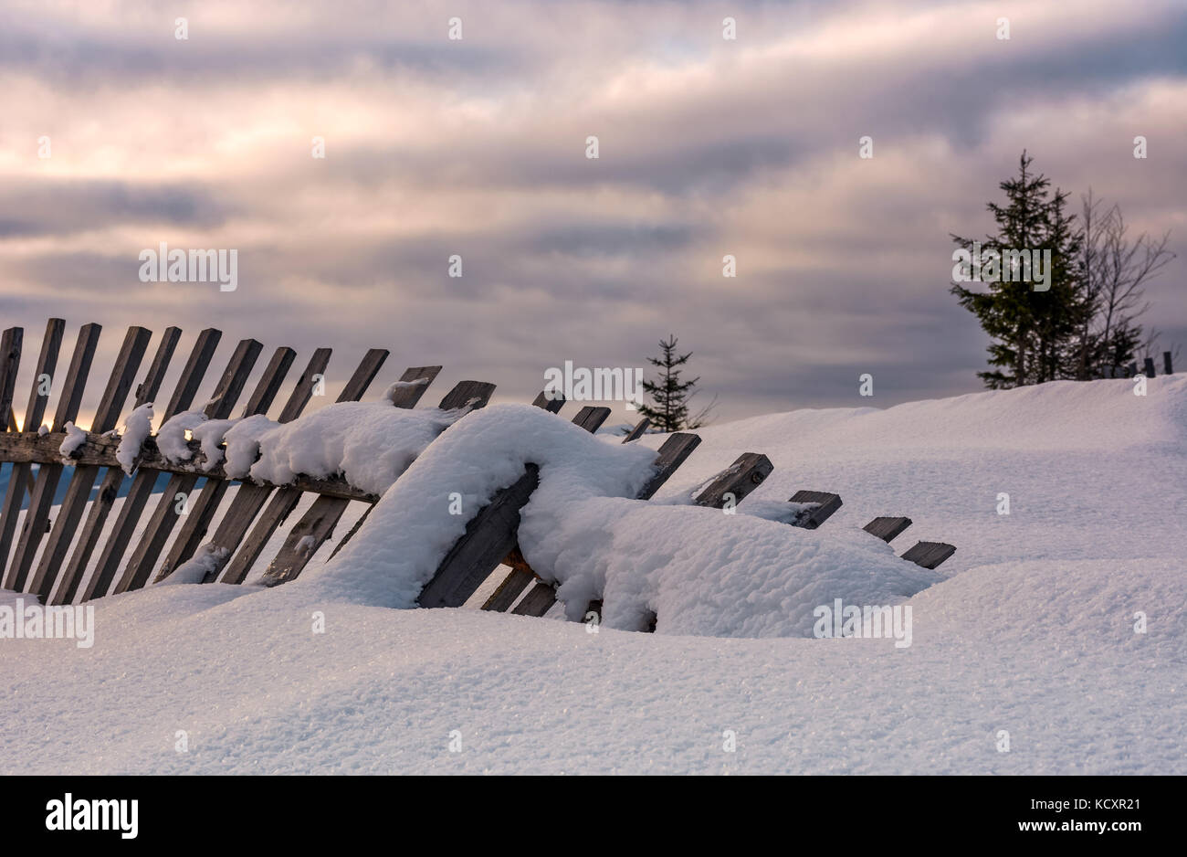 Caduto staccionata in legno sul pendio nevoso. incantevole paesaggio rurale in inverno Foto Stock