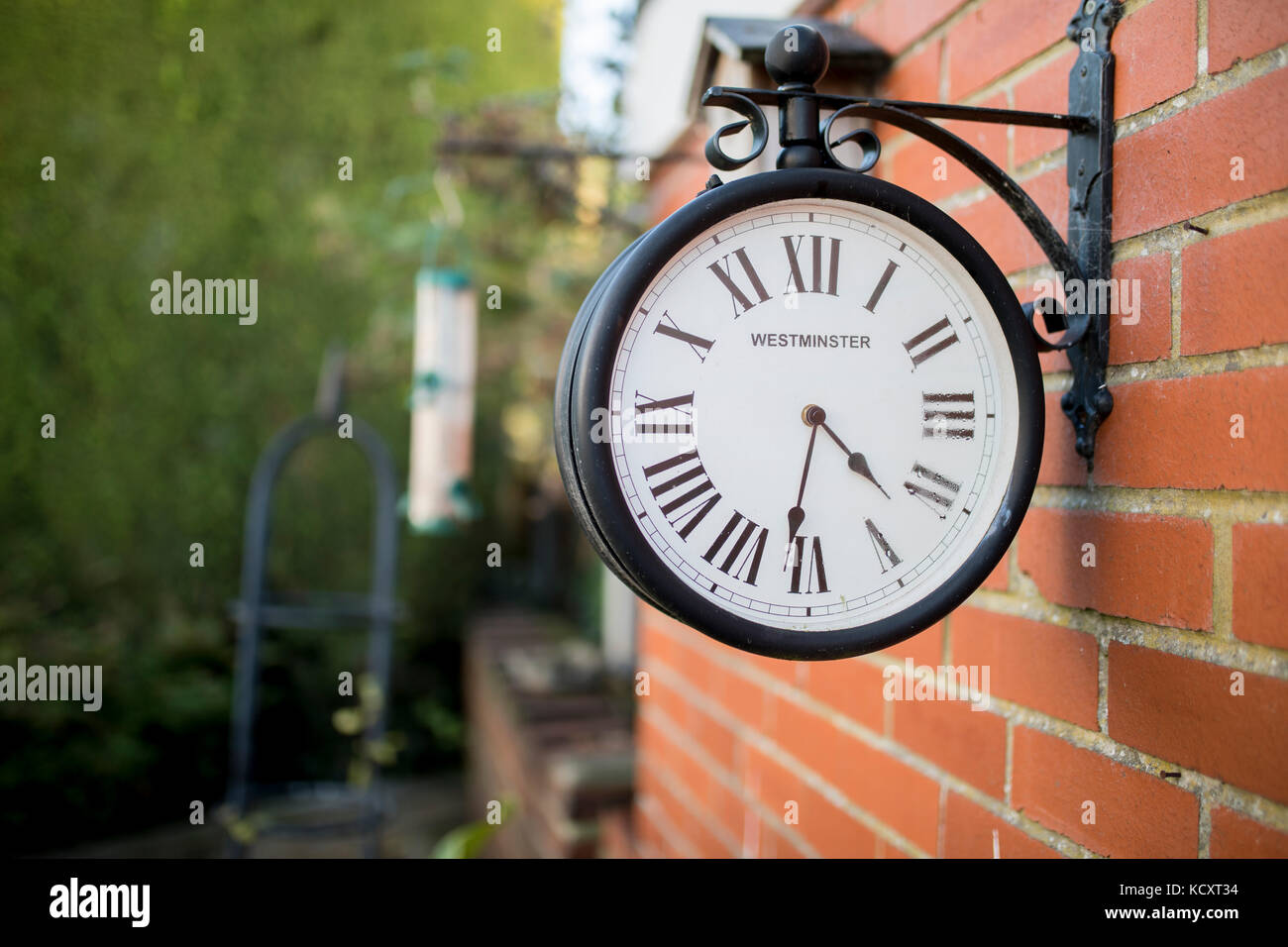Westminster antica stazione di ricerca orologio attaccato ad un muro di  mattoni in un tradizionale giardino inglese Foto stock - Alamy