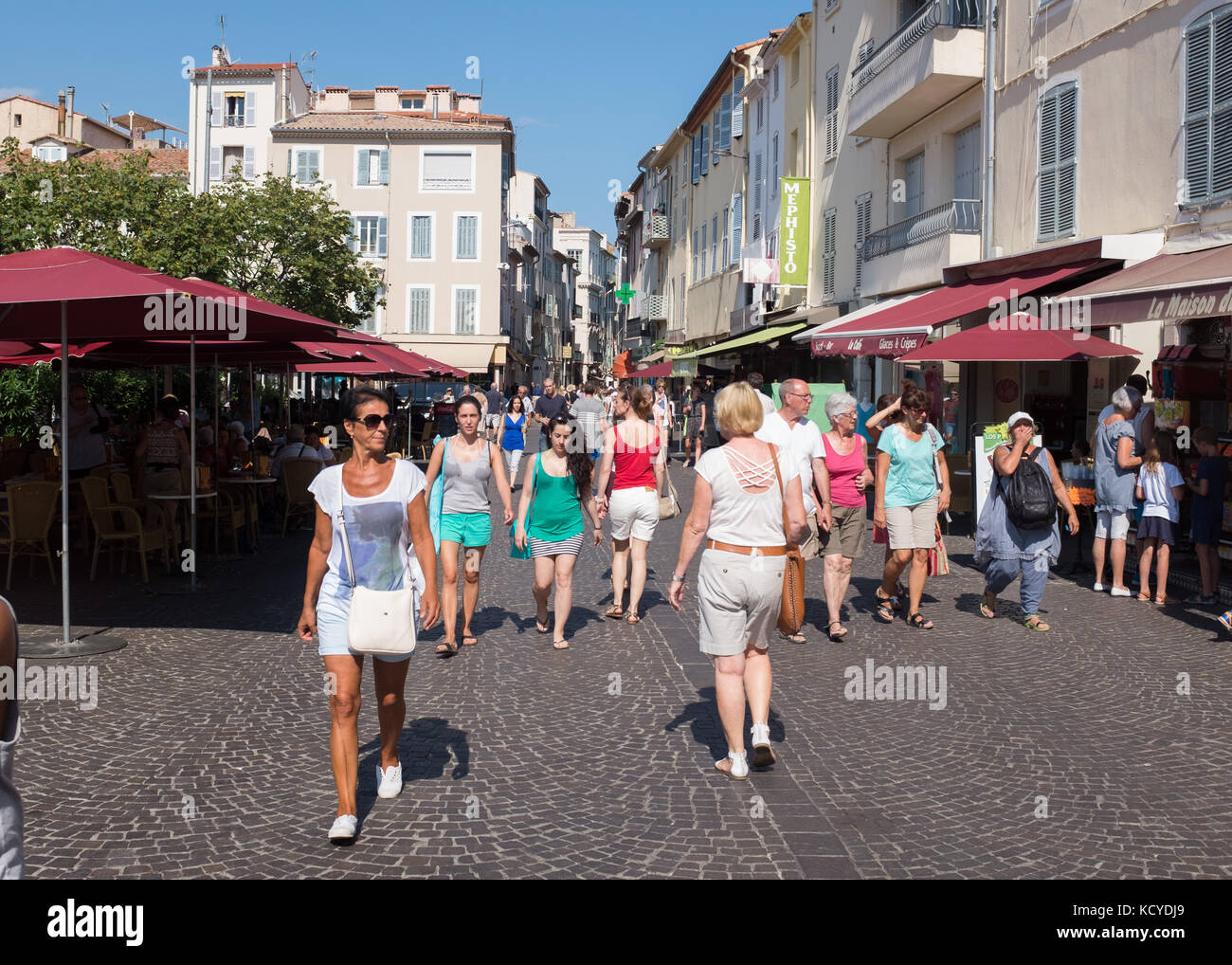 Persone che camminano lungo la strada accanto al caffè marciapiede della città vecchia, Antibes, Costa Azzurra, Provenza-Alpi-Costa Azzurra, Francia. Foto Stock