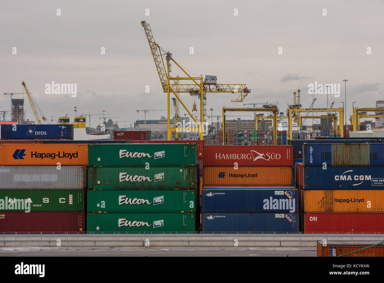 Esportare e importare merci in contenitori in attesa a Dublino docks con gru da carico in background. Foto Stock