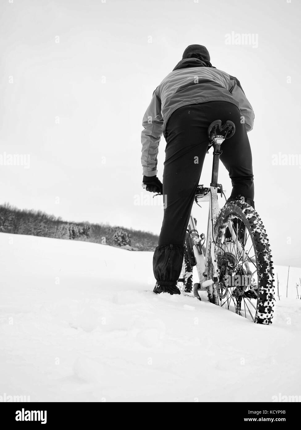 Sportivo con mountain bike perso nella neve. perso il percorso nel cumulo di neve profonda. fiocchi di neve di fusione su dark off road pneumatico. inverno meteo nel campo. Foto Stock