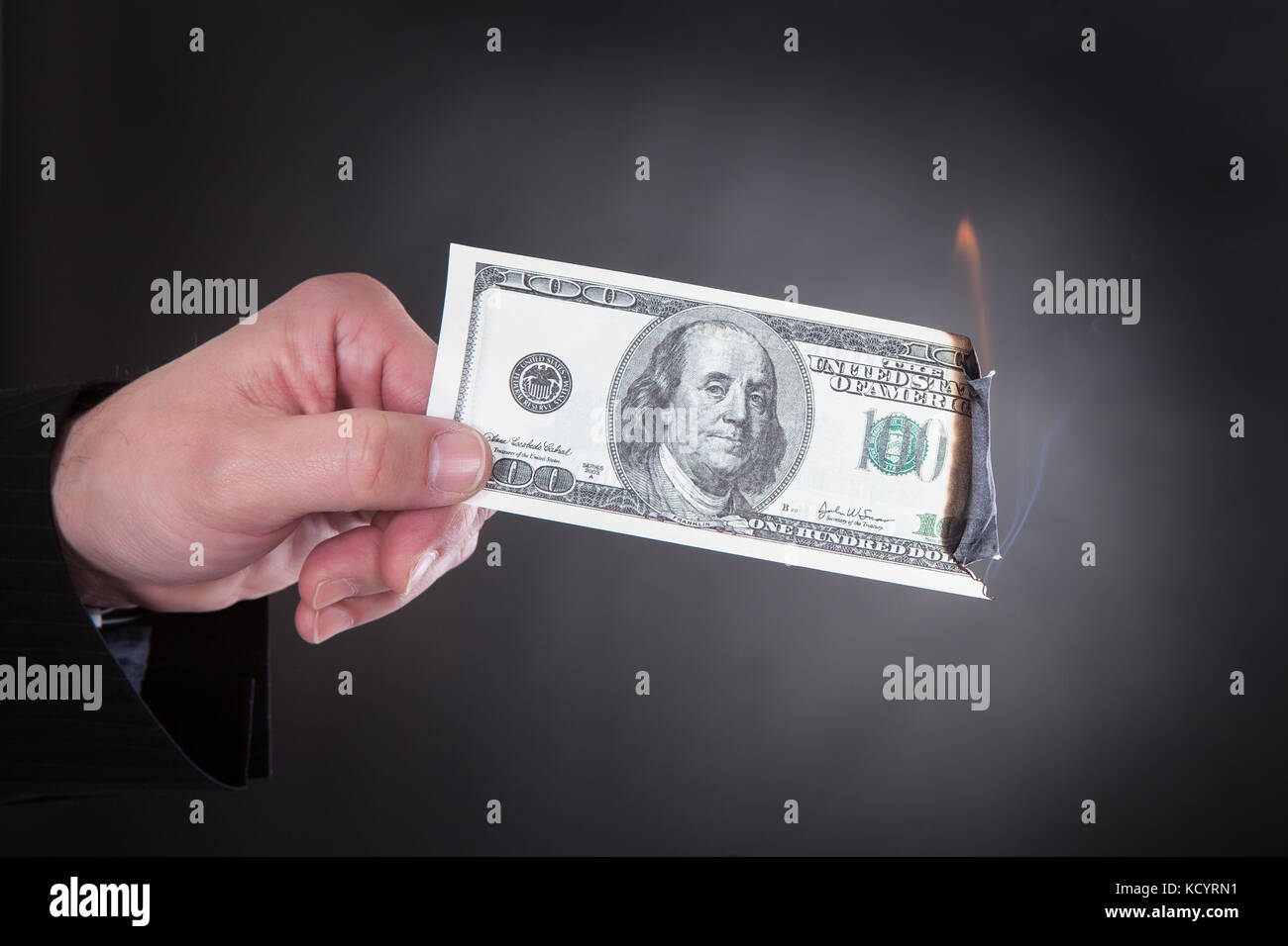 Close-up della mano che tiene la masterizzazione di banconota su sfondo nero Foto Stock