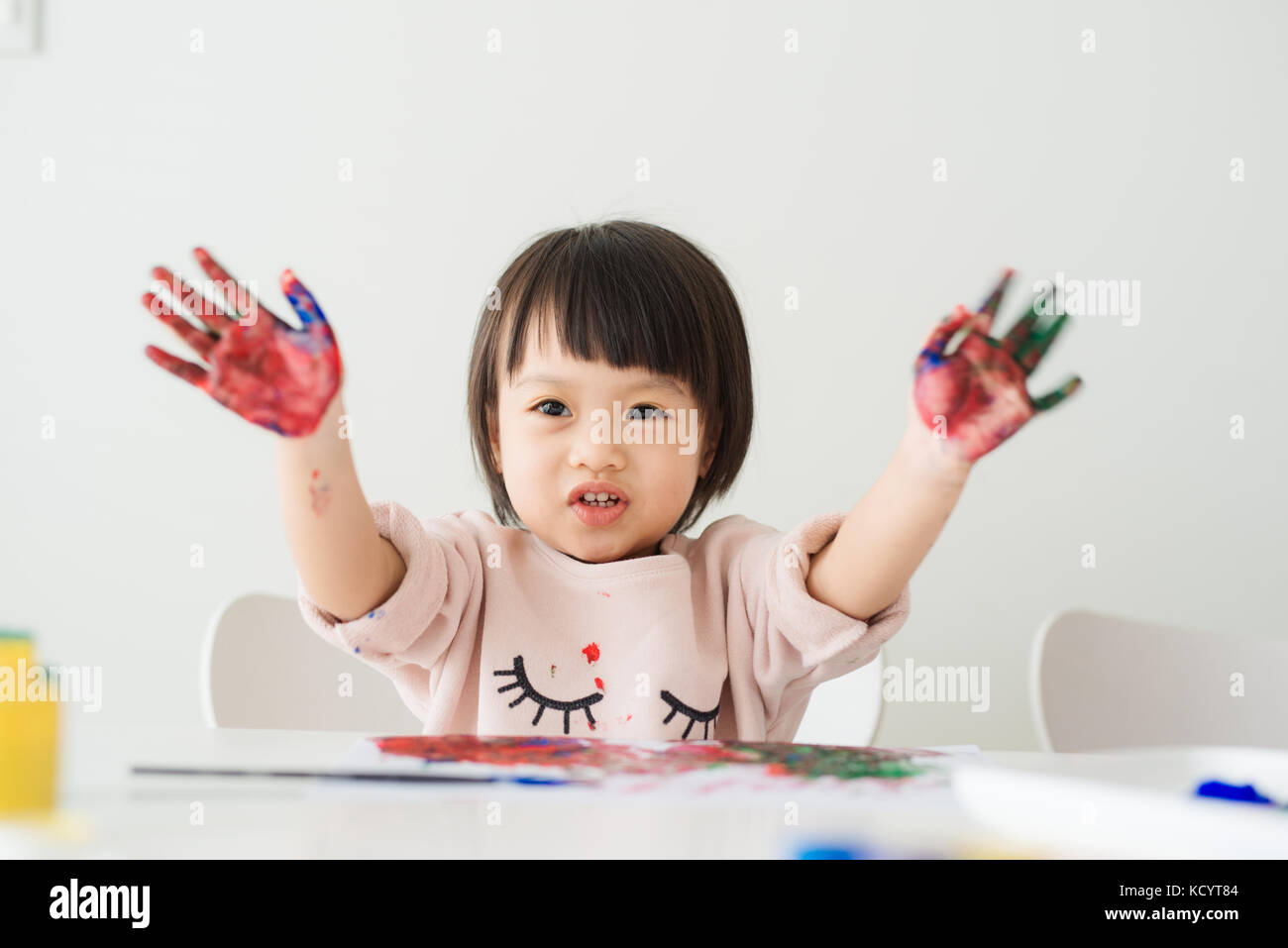 Carino ragazza asiatica che mostra la sua mani colorate Foto Stock