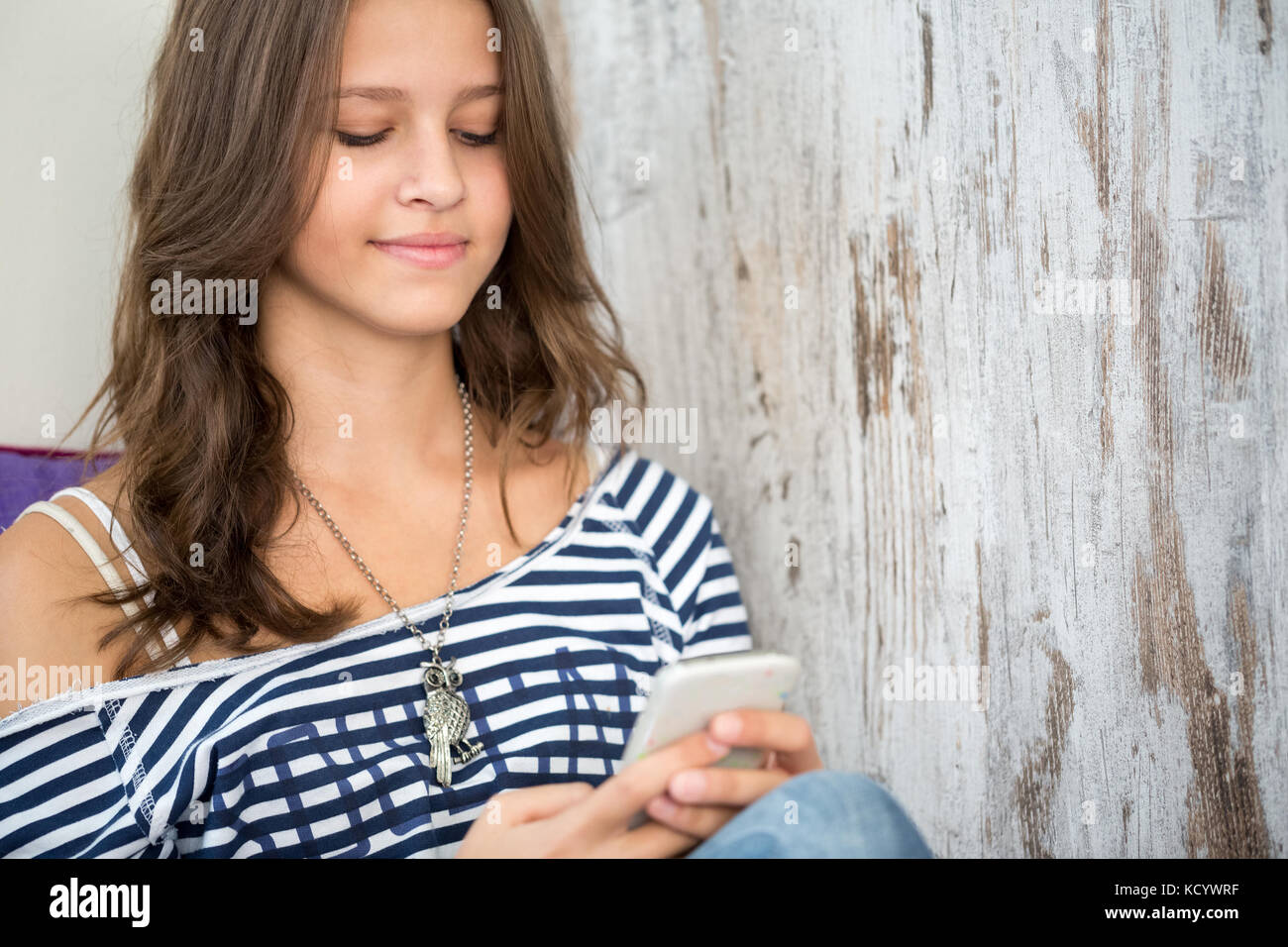 Carina ragazza adolescente concentrarsi sul telefono, messaggi SMS Foto Stock
