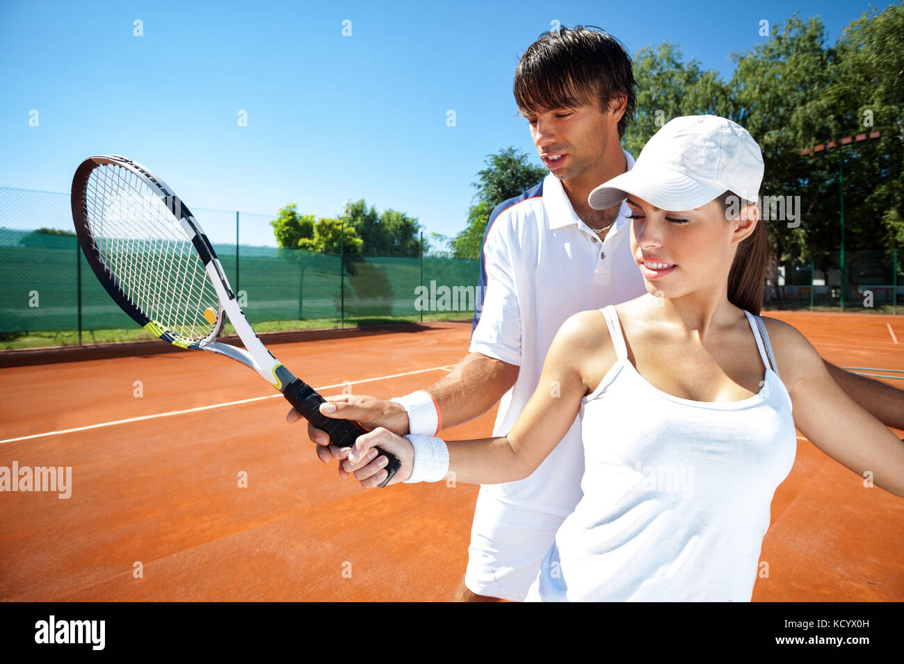 Donna e maschio istruttore di tennis Racchetta praticanti il controllo sul campo da tennis Foto Stock