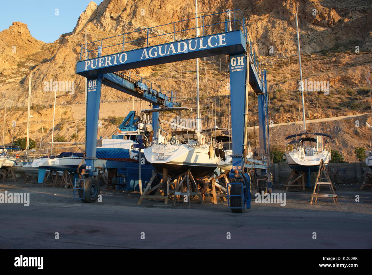 Sailing yacht in cantiere essendo messo in imbracature di sollevamento prima di essere trasportato Foto Stock