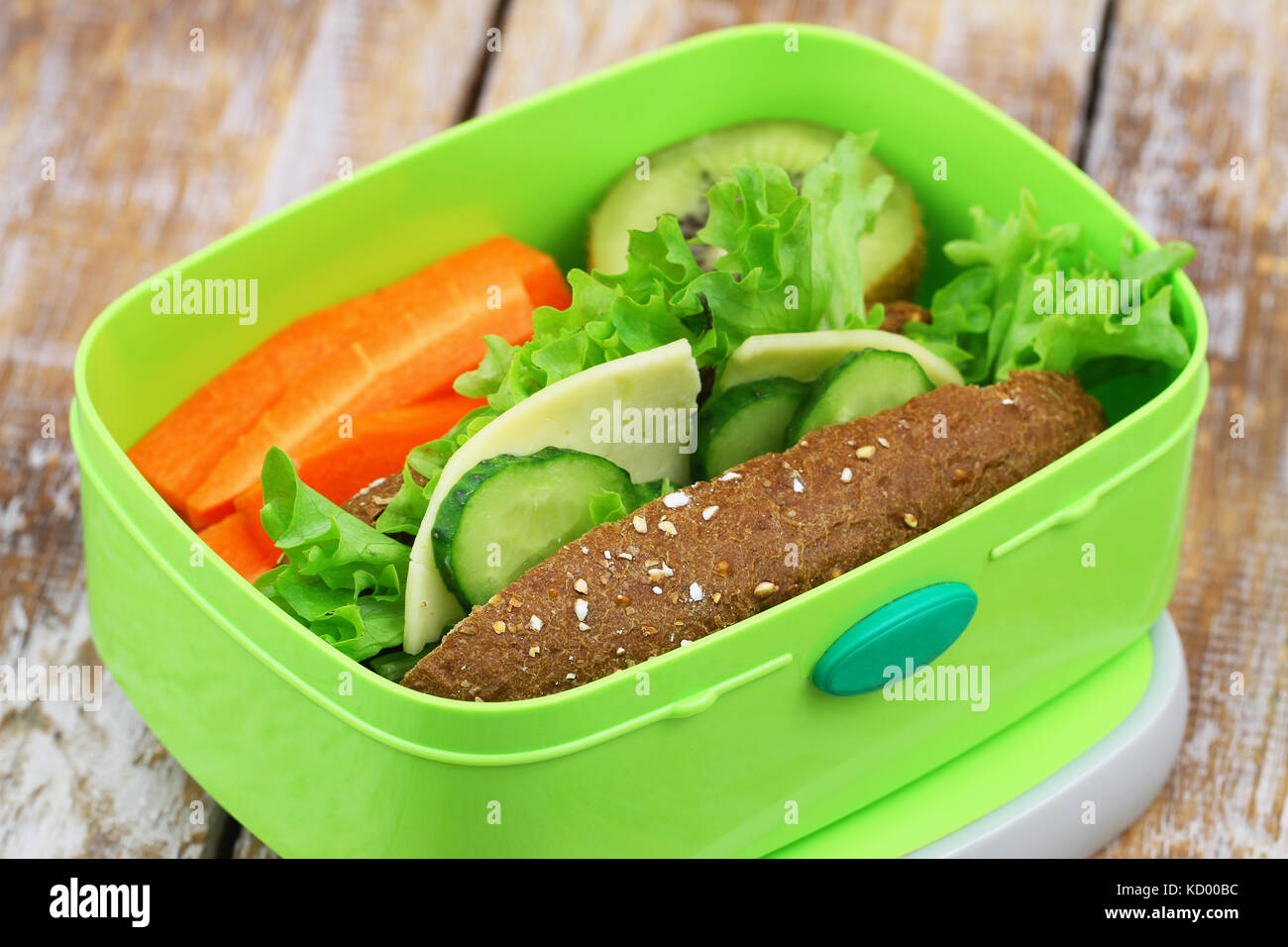 Pranzo sano scatola contenente formaggio marrone sandwich con lattuga croccante di carote e kiwi Foto Stock