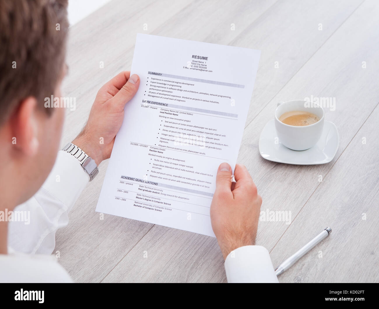 Close-up di imprenditore la lettura di riprendere con tazza da tè sulla scrivania Foto Stock