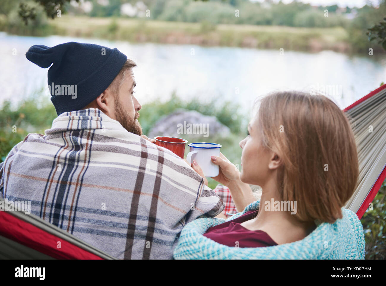 Vista posteriore del giovane in amaca holding tazze di smalto, Cracovia, malopolskie, Polonia, europa Foto Stock