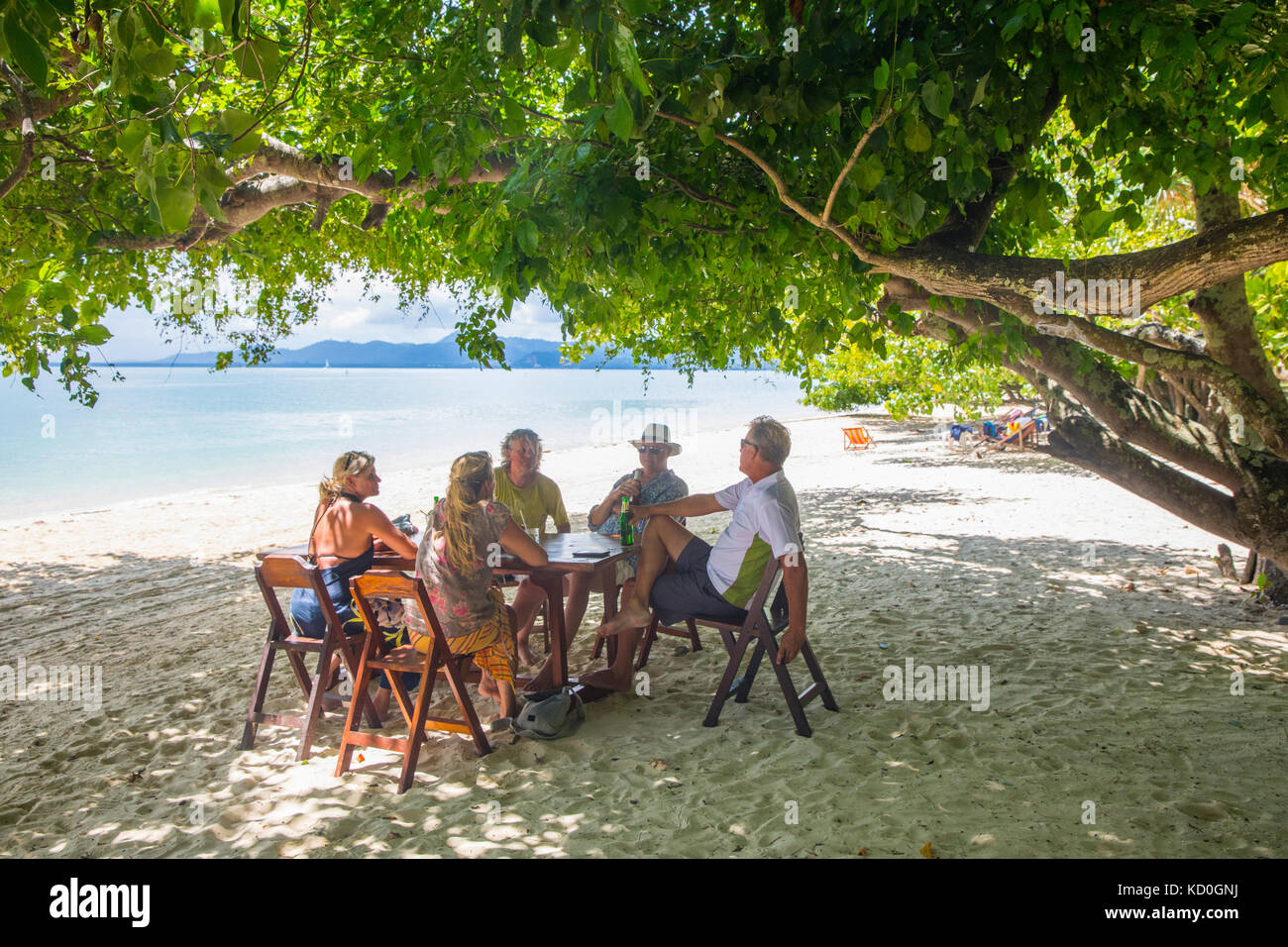 Gli amici in un momento di relax a tavolo da pranzo sulla spiaggia, koh Rang Yai, Thailandia, asia Foto Stock