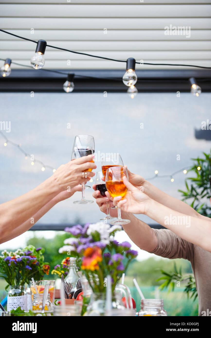 Mani di uomini e donne crescere una famiglia vino toast al patio tabella Foto Stock