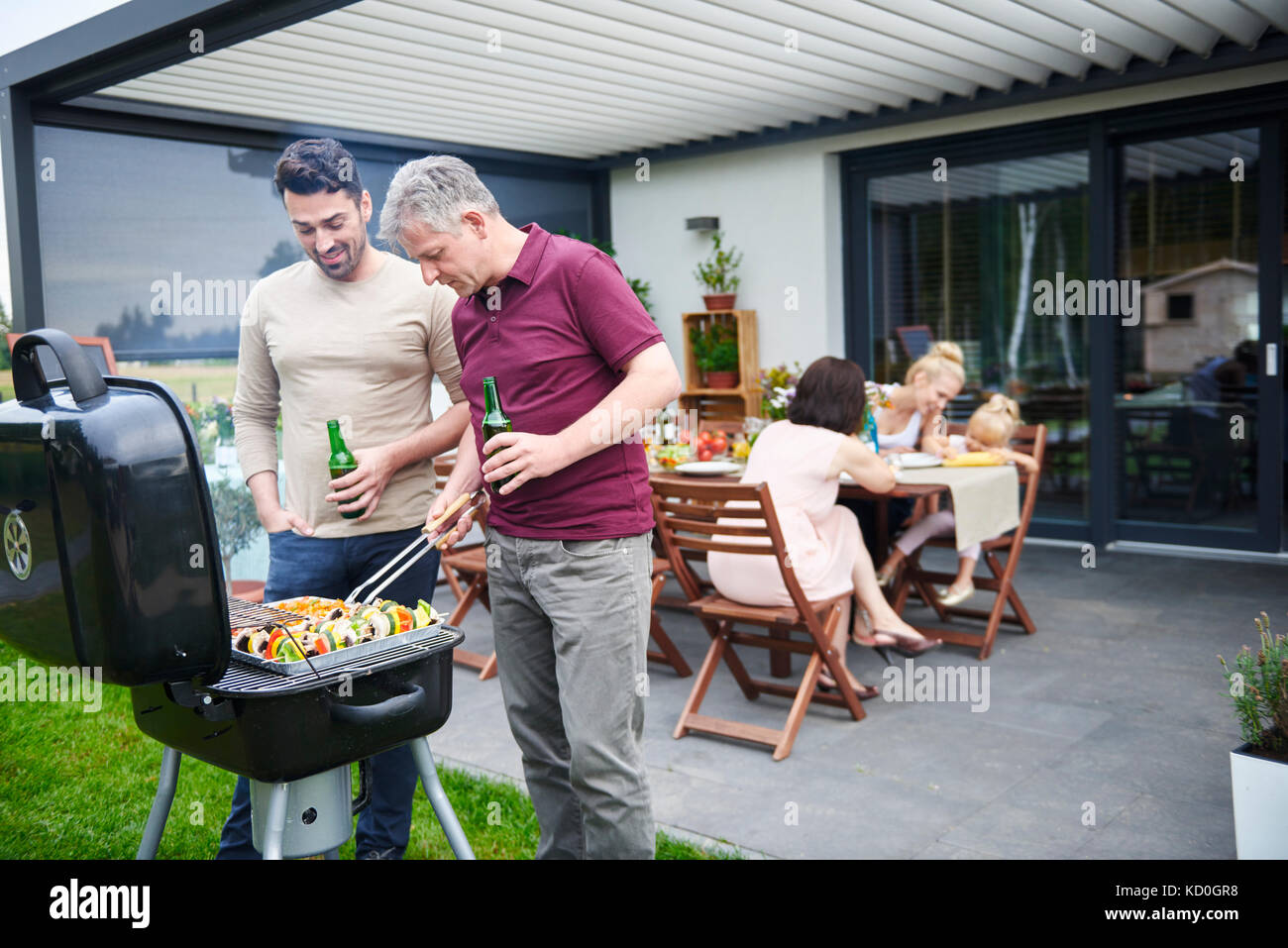 Matura e metà uomo adulto grigliate a pranzo di famiglia sul patio Foto Stock