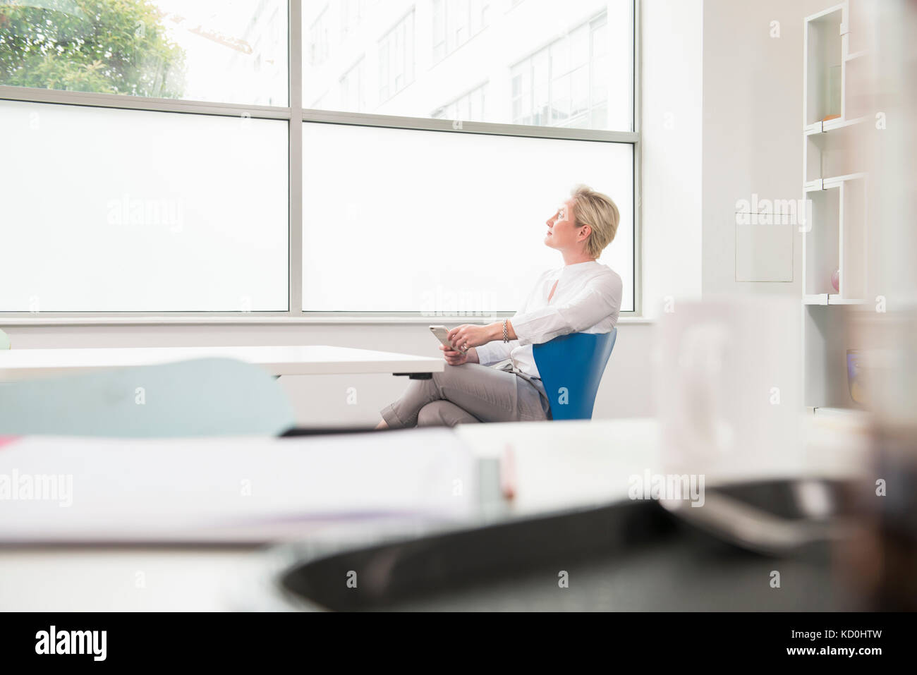 La donna nel pensiero profondo guardando fuori della finestra di ufficio Foto Stock