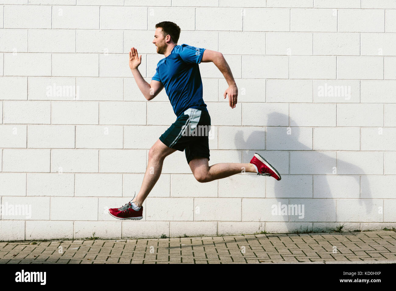 Giovane maschio velocità runner che corre lungo il marciapiede Foto Stock