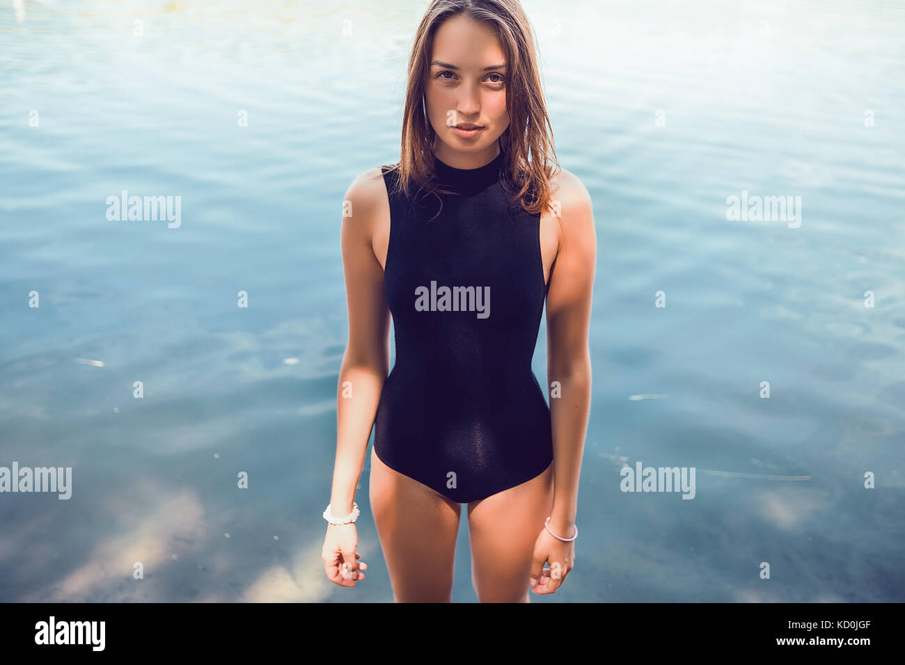 Ritratto di donna che indossa il costume da bagno in piedi in acqua guardando la fotocamera Foto Stock