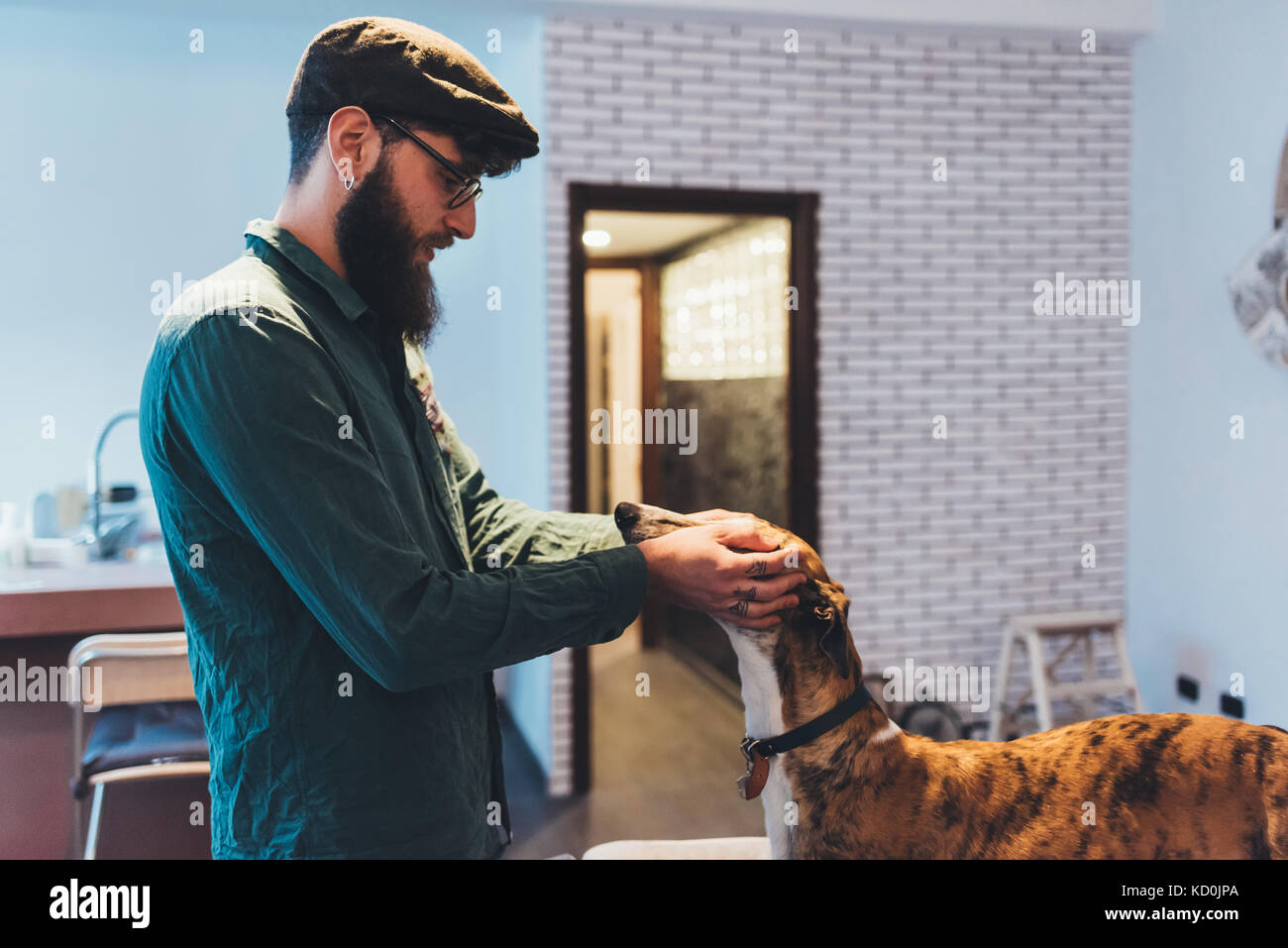 L uomo nel tappo piatto petting cane in appartamento Foto Stock