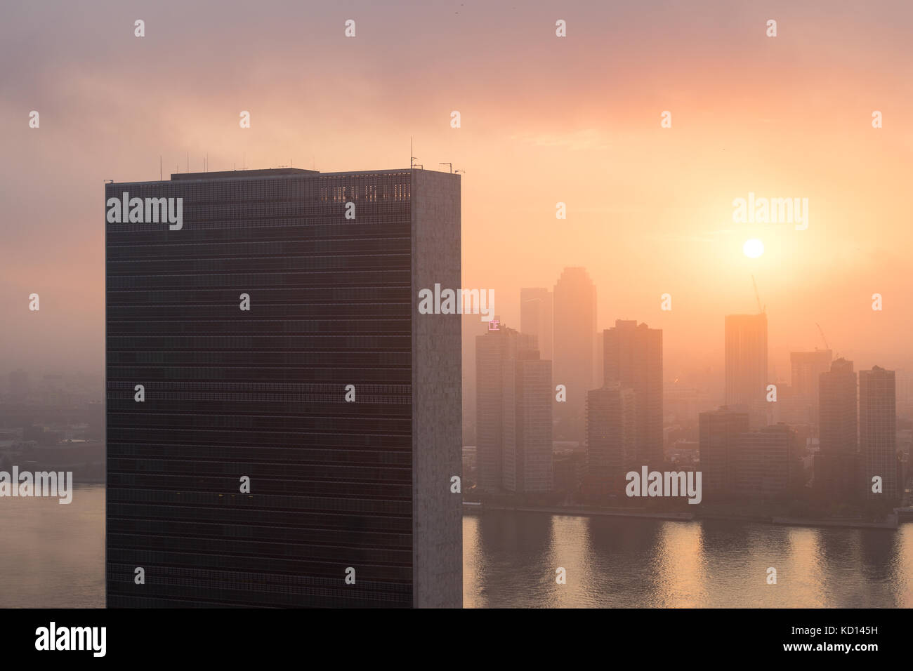 Colorato sunrise cielo dietro onu nazioni unite segretariato edificio. East River e Long Island City skysrapers nella nebbia dietro di esso. Foto Stock