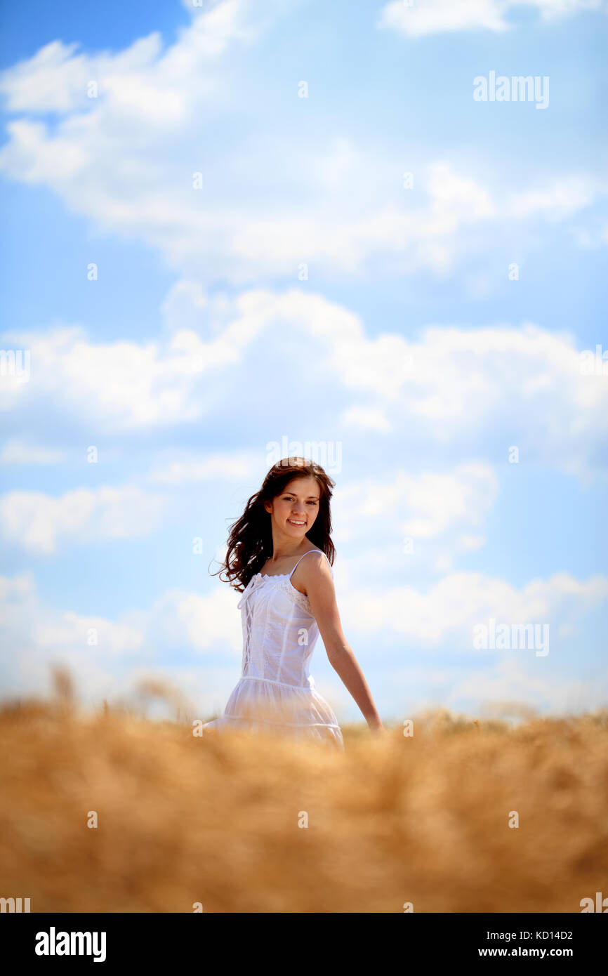 Felice giovane donna godendo di sun sul campo di grano Foto Stock