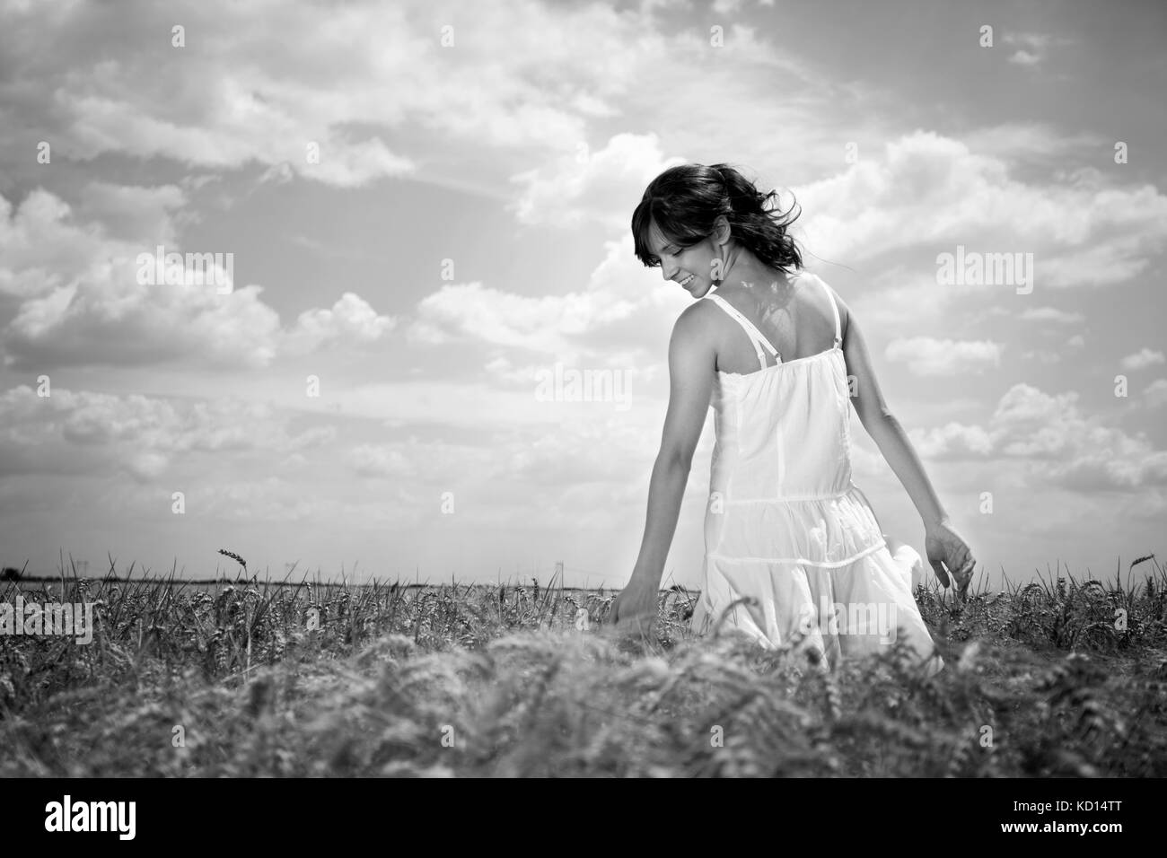 Giovane donna camminare attraverso il campo di grano di toccare il frumento, in bianco e nero Foto Stock