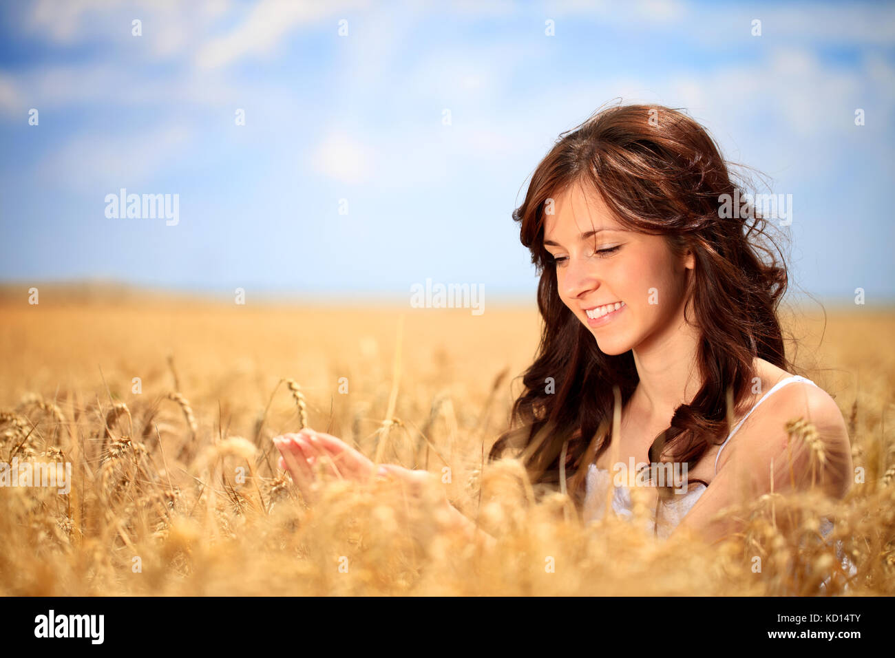 Sorridente giovane donna in golden frumento prendersi cura del grano Foto Stock