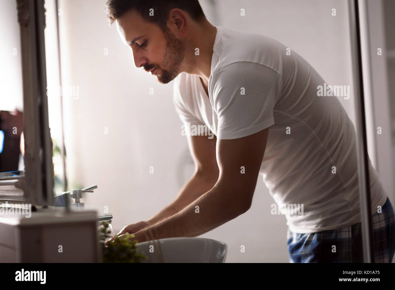 Bel giovane faccia il lavaggio in bagno Foto Stock