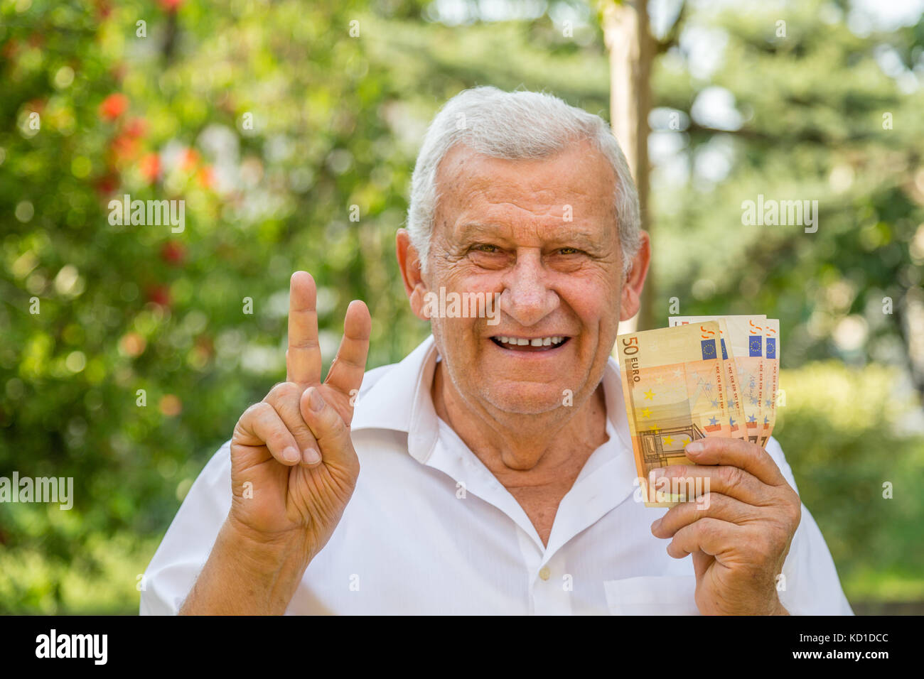 Il vecchio uomo che mostra di euro in un giardino verde Foto Stock
