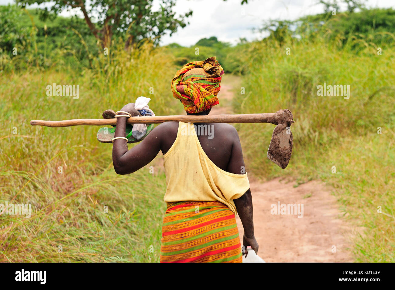 Donna africana di andare a lavorare con la zappa nel campo Foto Stock