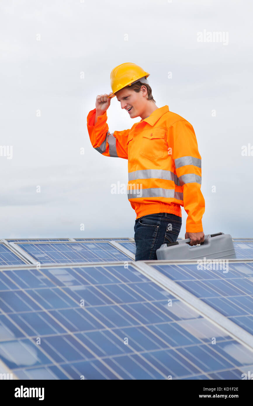 Happy Engineer con Toolkit in piedi di fronte al pannello solare Foto Stock