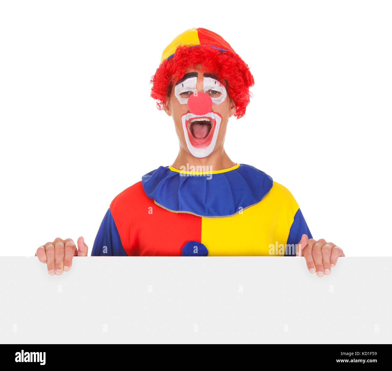 Ritratto di un felice Joker Holding targhetta in bianco su sfondo bianco Foto Stock