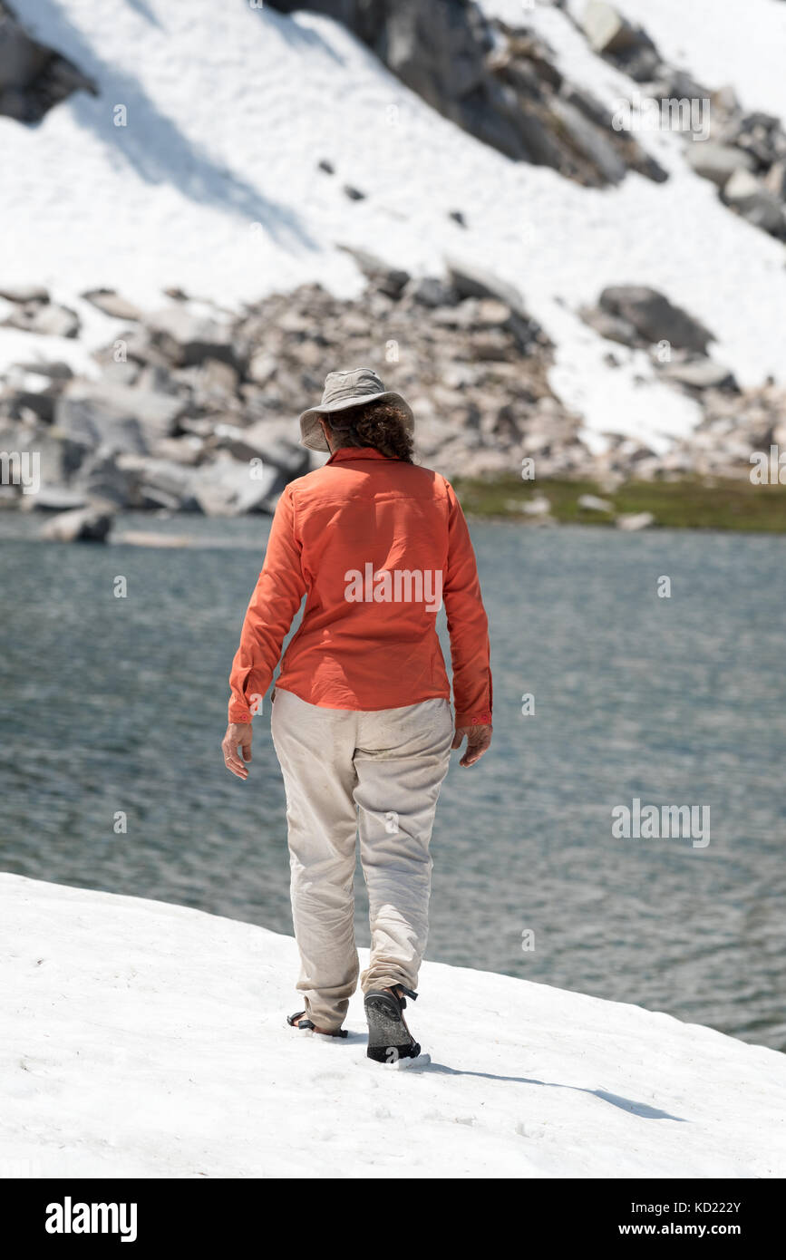 Donna che indossa sandles camminando sul snowfield accanto a un lago in oregon wallowa della montagna. Foto Stock