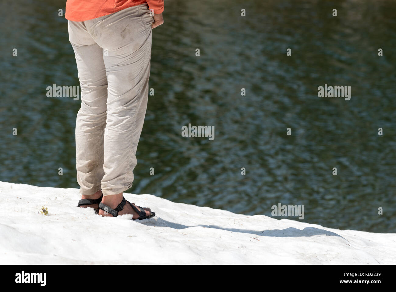 Donna che indossa sandles permanente sulla snowfield accanto a un lago in oregon wallowa della montagna. Foto Stock