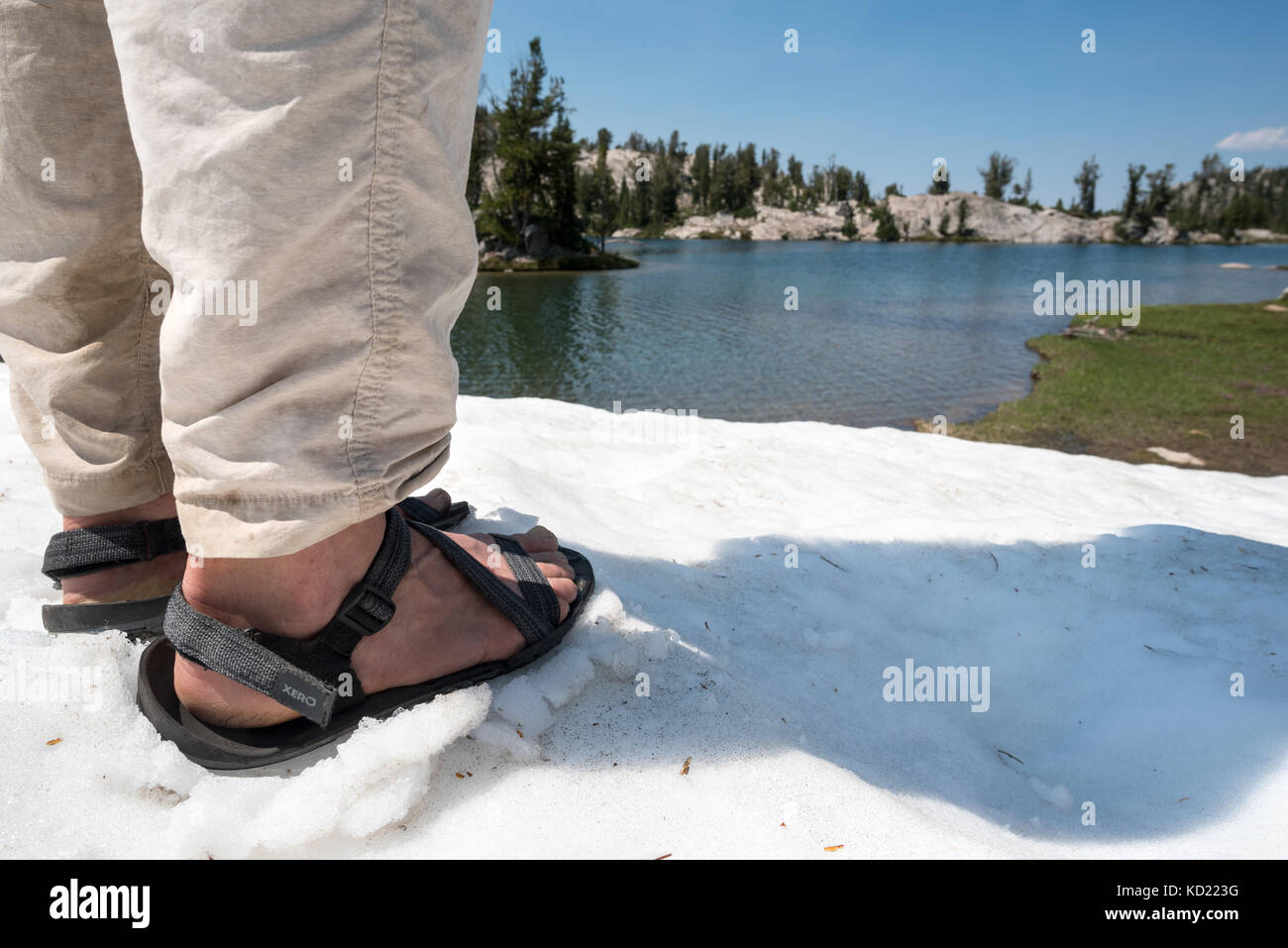Donna che indossa sandles permanente sulla snowfield accanto a un lago in oregon wallowa della montagna. Foto Stock