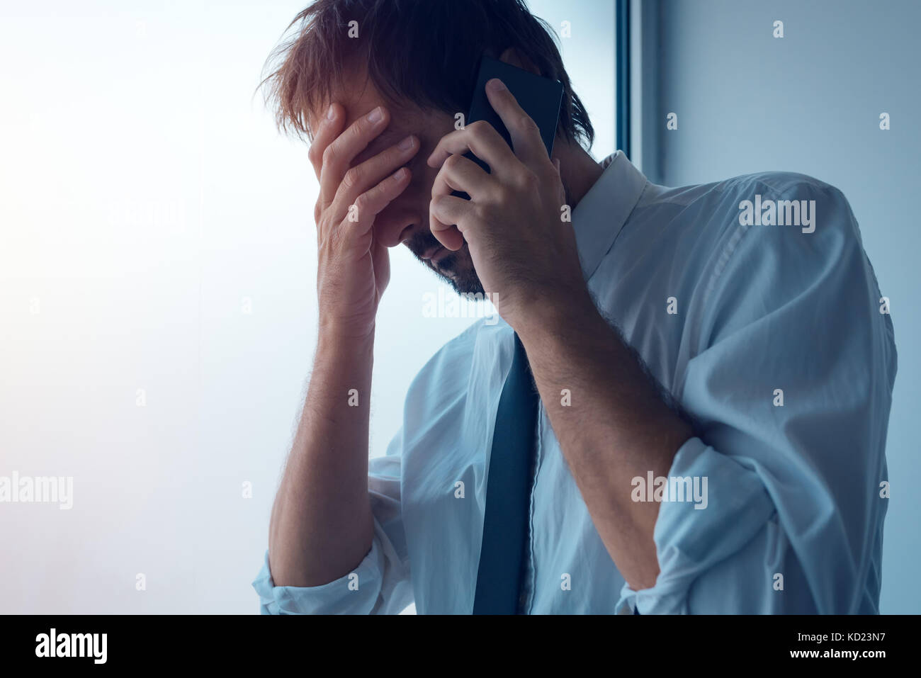 Imprenditore in piedi accanto alla finestra di ufficio e utilizza lo smartphone. business comunicazione tramite messaggi sms o mobile apps. persona d'affari ricevuto cattive Foto Stock