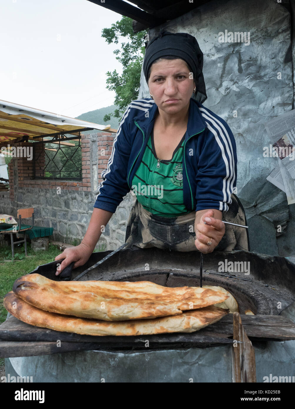 Qabala, Azerbaigian - 20 Maggio 2017 : il ritratto di una donna che fa il pane tradizionale . un apposito gancio di metallo è usato per tenere il pane alle pareti o prendere Foto Stock