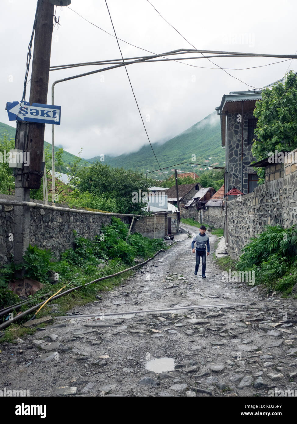 Ragazzo waliking in una strada di Kish, un insediamento rurale nel distretto di sheki, nord Azerbaigian Foto Stock