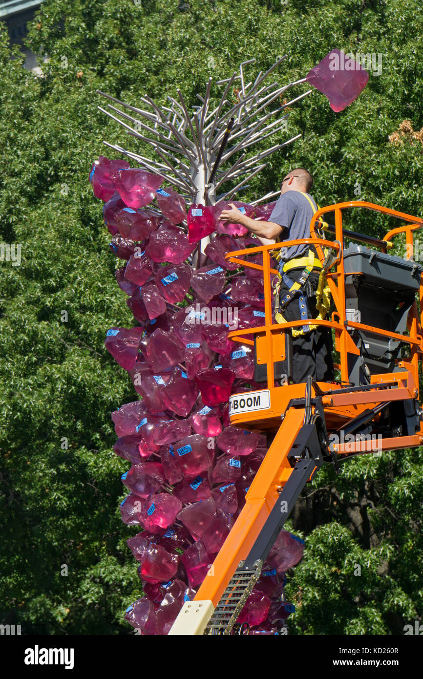 Un operaio installazione di Dale Chihuly's Rose torre di cristallo sculture di vetro adiacente a Union Square Park di Lower Manhattan, New York City. Foto Stock