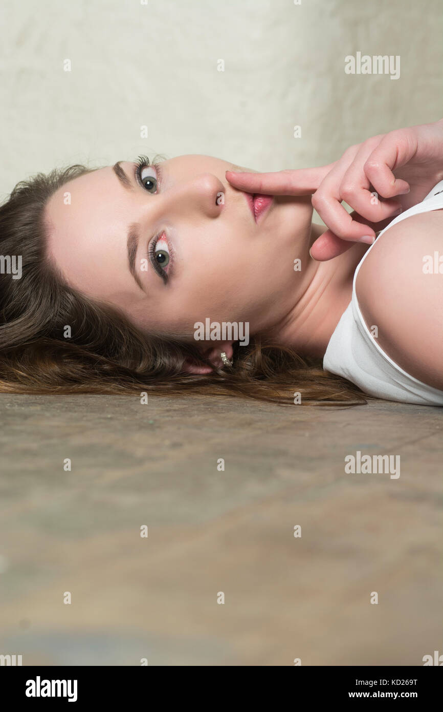 Bella giovane donna recante sul pavimento la mano sulla bocca esigente silenzio Foto Stock