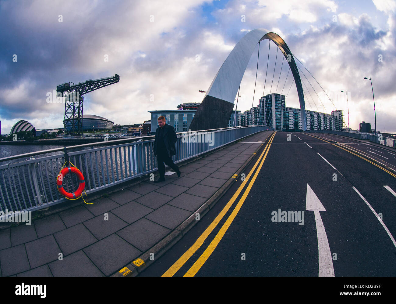 Uomo che cammina al di sopra del ponte Squinty a Glasgow, aka il Clyde Arc, con la gru Finnieston , SSE Idro e SECC Armadillo in background Foto Stock