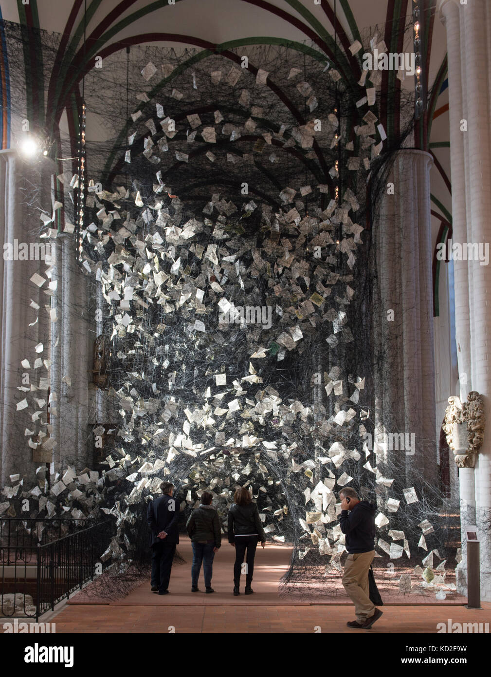 I visitatori si trovano nell'installazione artistica "Lost Words" dell'artista giapponese Chiharu Shiota nella chiesa di San Nicola a Berlino, Germania, 9 ottobre 2017. Tesseva 750 chilometri di fili e 4000 pagine della Bibbia in 100 lingue in un'unica opera nella navata centrale della chiesa. La ragnatela gigante può essere visitata fino al 19 novembre 2017. Foto: Paul Zinken/dpa Foto Stock