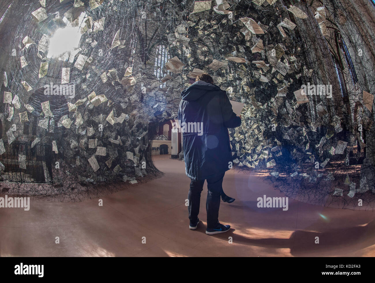 I visitatori si trovano nell'installazione artistica "Lost Words" dell'artista giapponese Chiharu Shiota nella chiesa di San Nicola a Berlino, Germania, 9 ottobre 2017. Tesseva 750 chilometri di fili e 4000 pagine della Bibbia in 100 lingue in un'unica opera nella navata centrale della chiesa. La ragnatela gigante può essere visitata fino al 19 novembre 2017. Foto: Paul Zinken/dpa Foto Stock