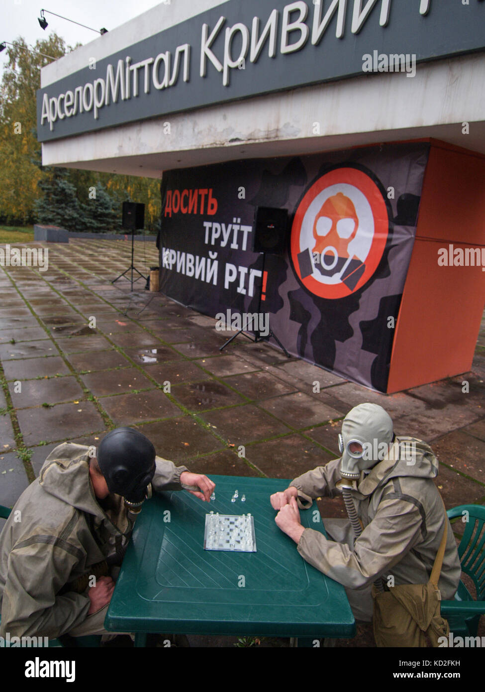 Kryvyi Rih, Ucraina - 9 ottobre 2017: Due uomini indossati maschere antigas sui volti che giocano a scacchi vicino ad ArcelorMittal Kryvyi Rih monumento del marchio PJSC all'interno dell'incontro di protesta contro l'inquinamento atmosferico credito: Dmytro Aliokhin/Alamy Live News Foto Stock