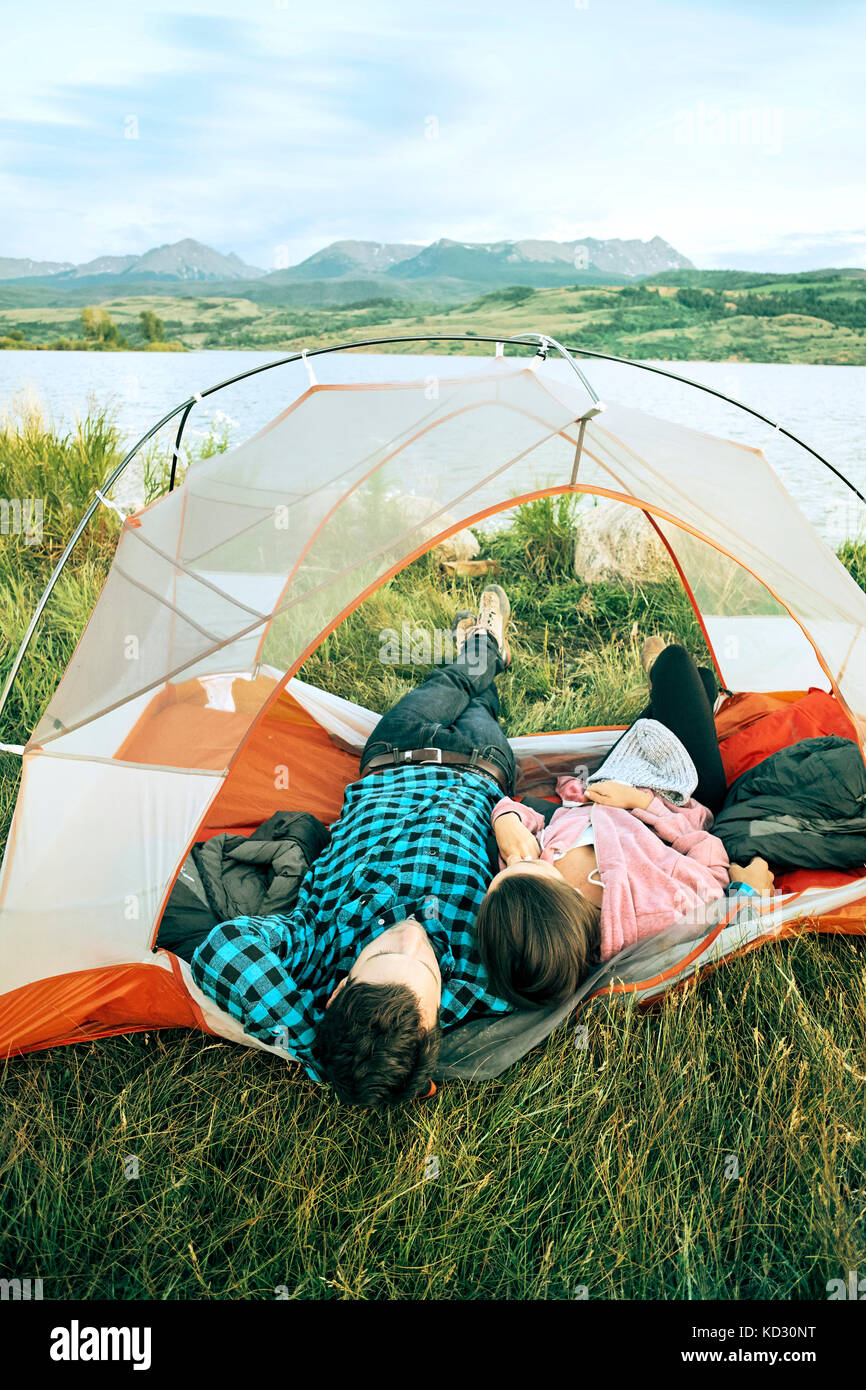 Coppia giacendo in tenda, teste al di fuori della tenda, vista posteriore, Heeney, Colorado, Stati Uniti Foto Stock