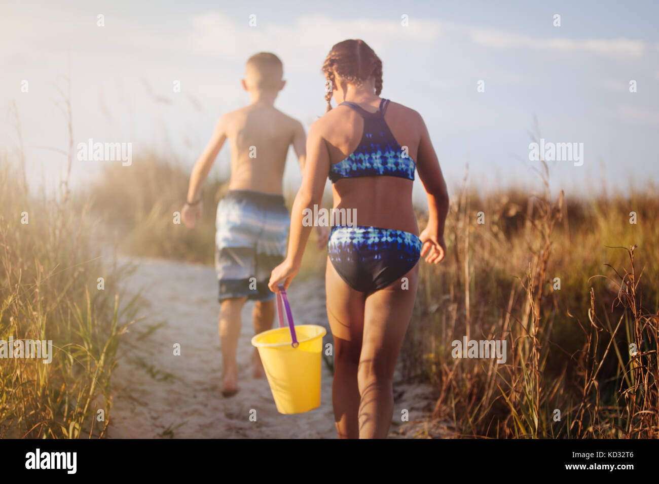 Vista posteriore del ragazzo e una ragazza camminare su dune erbose, North Myrtle Beach, Carolina del Sud, Stati Uniti, America del Nord Foto Stock