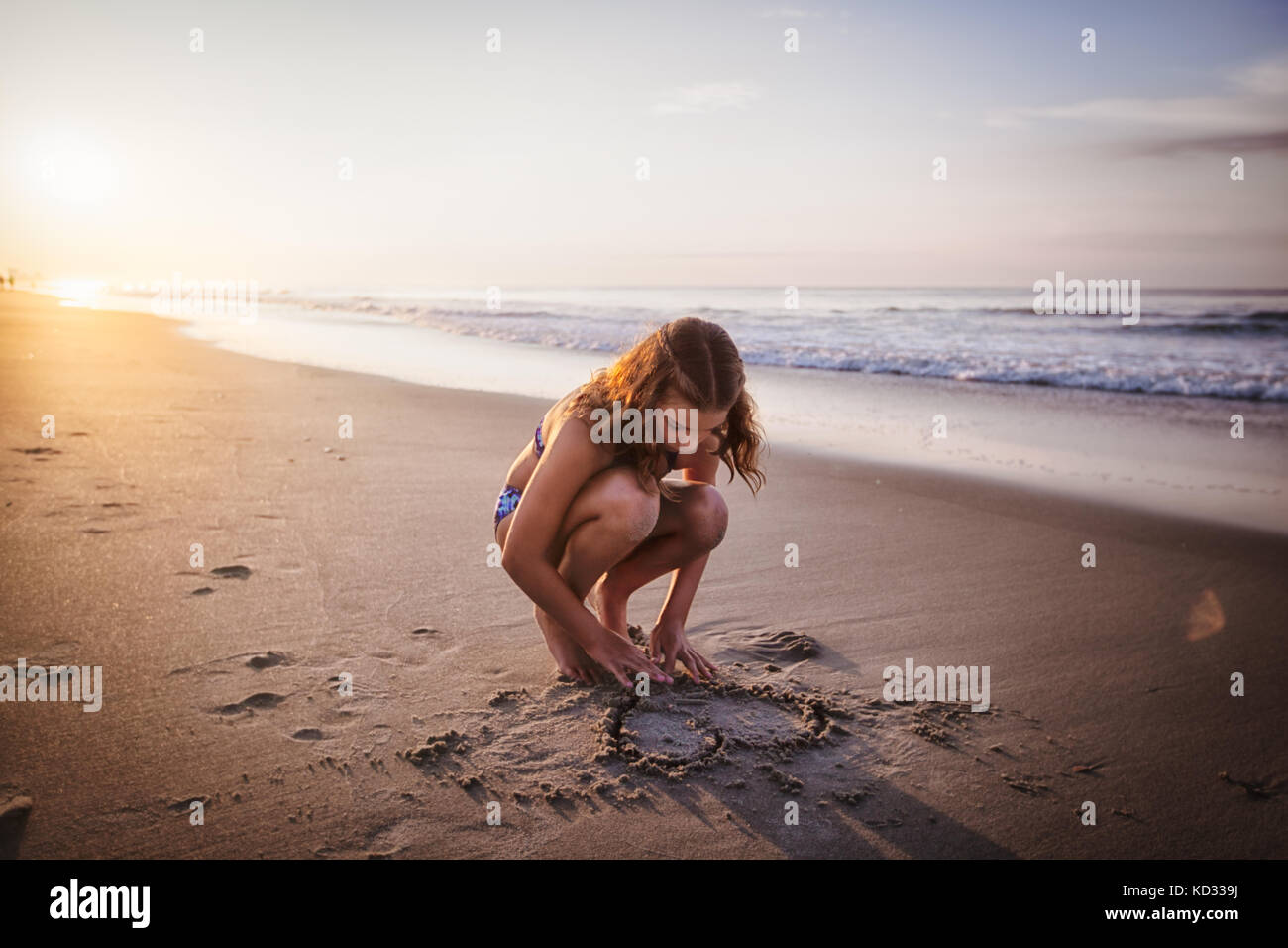 Ragazza cuore di disegno nella sabbia sulla spiaggia Foto Stock