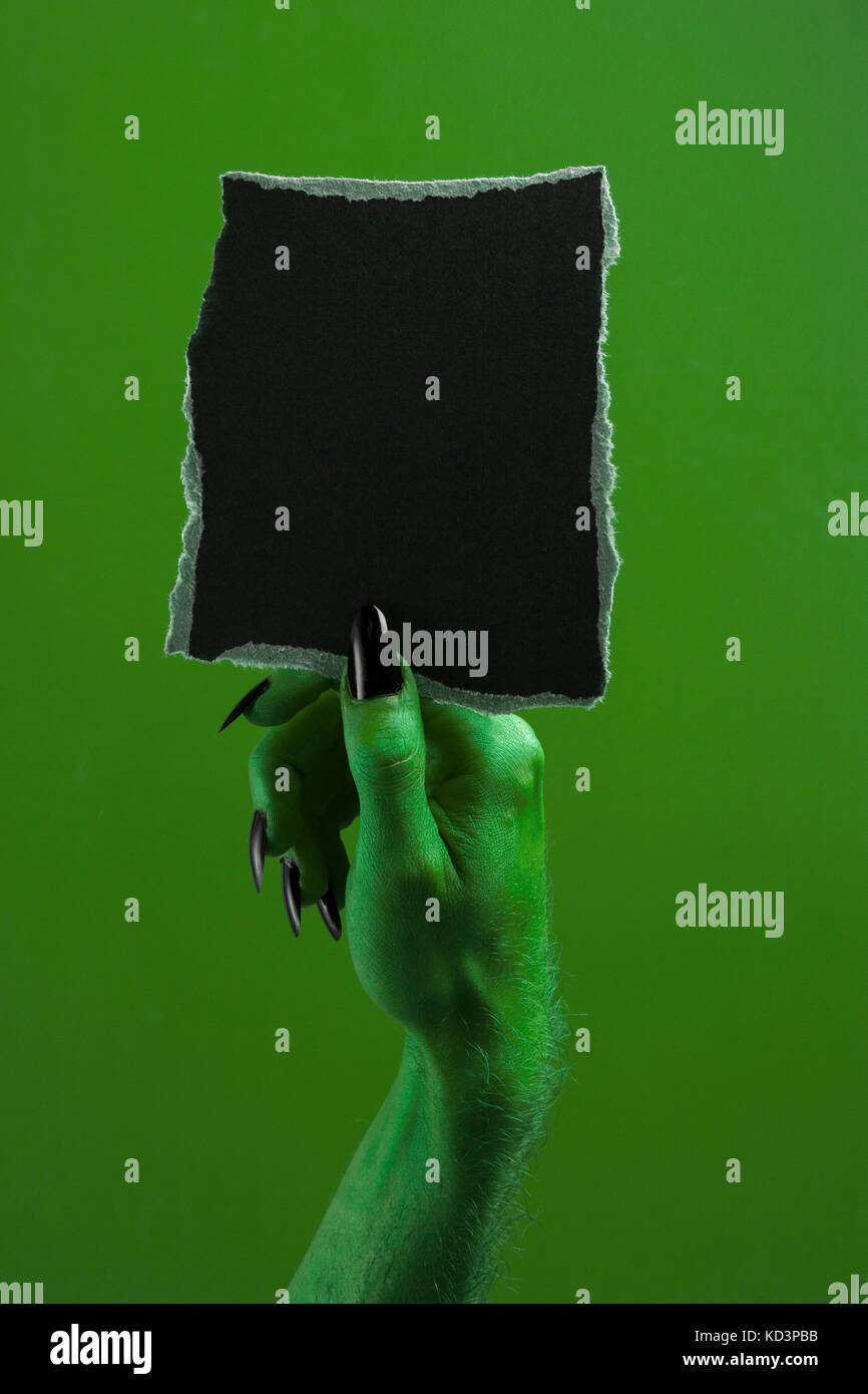 Halloween streghe verdi o zombie monster mano che tiene un cartello bianco Foto Stock