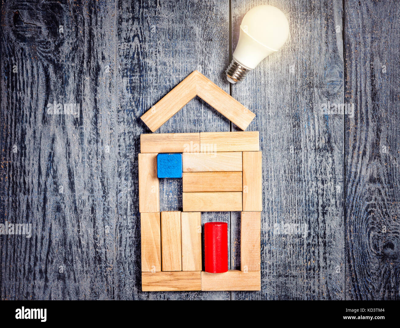 Forma di casa sopra albero in legno scuro e sfondo lampadina led. imitazione di riscaldamento di rame o caldaia e condizionatore aria Foto Stock