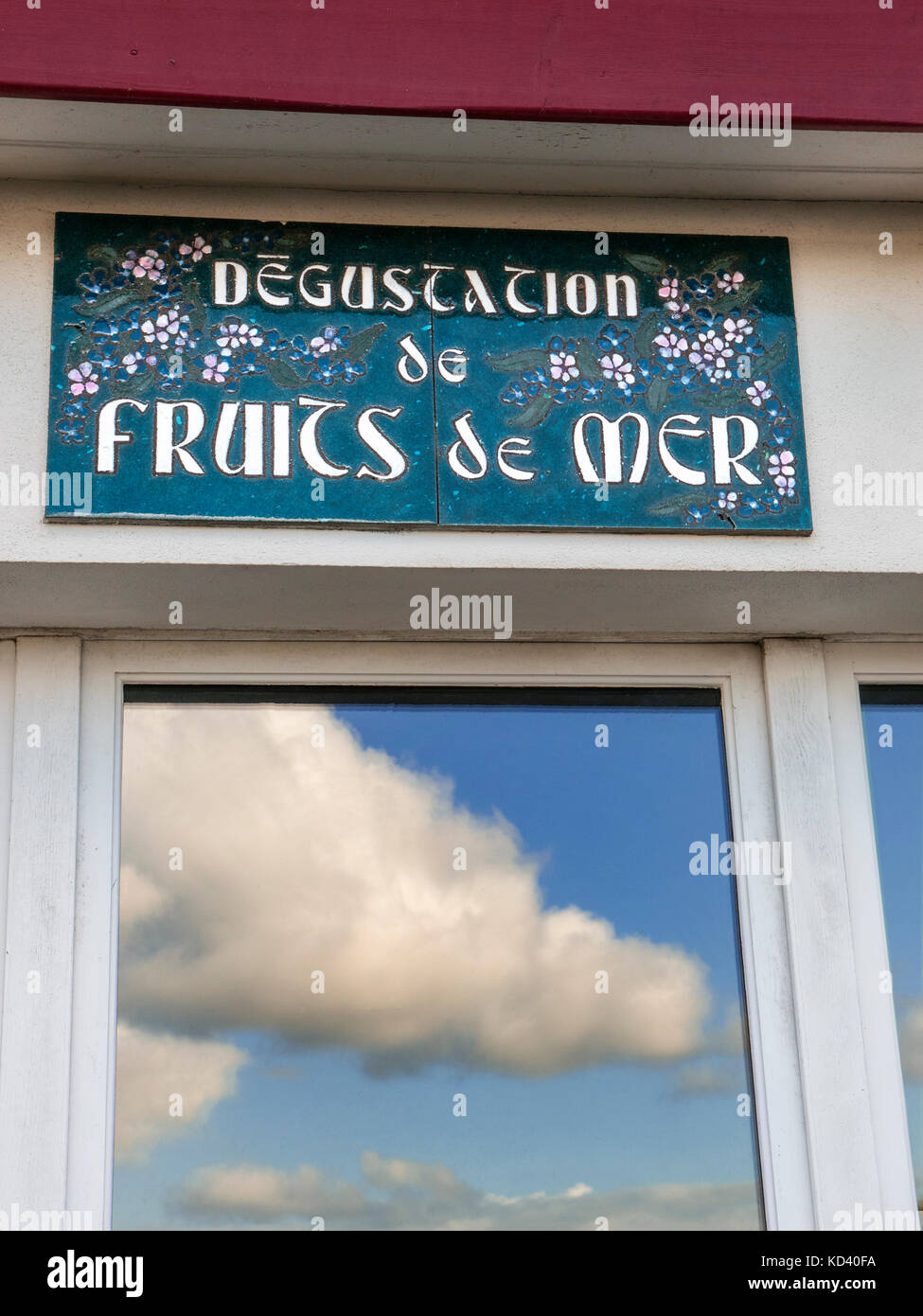 Rustico ristorante francese pubblicità segno 'degustation de fruits de mer" (degustazione dei frutti di mare) con l'azzurro del cielo e il porto si riflette nella finestra Foto Stock