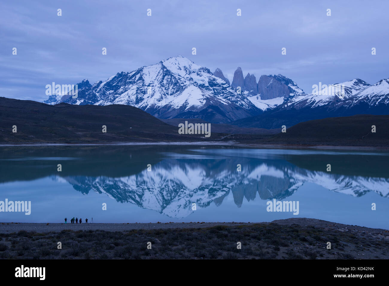 Torres del Paine montagne che si riflettono sulla superficie della laguna amarga, con i turisti per scattare delle foto in primo piano Foto Stock
