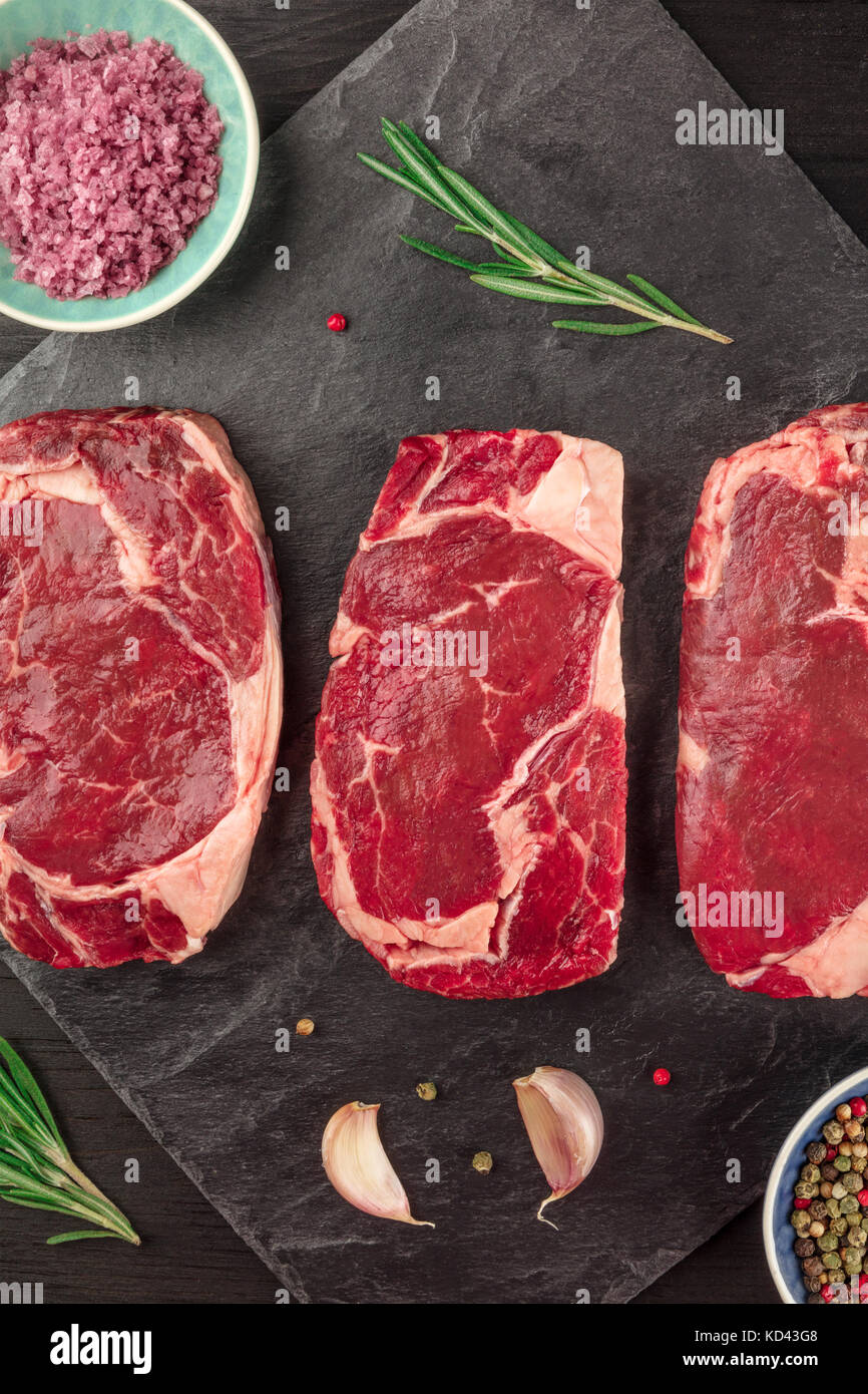 Tre Fette Di Carne Cruda Su Nero Con Il Condimento Foto Stock Alamy